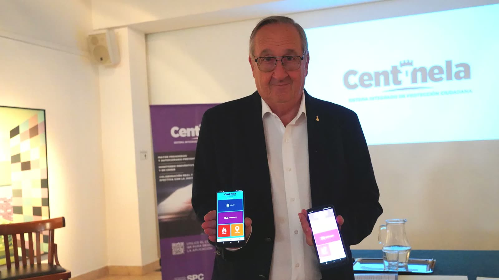 El intendente Miguel Lunghi sostiene dos teléfonos con la aplicación Centinela durante el lanzamiento